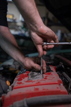 pexels photo 8470250 8470250 A mechanic uses a socket wrench to repair a car engine in a garage setting.